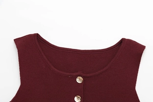 Détail de l'encolure d'un gilet en tricot bordeaux avec boutons métalliques dorés