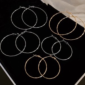 Detailed set of gold and silver hoop earrings with textured finish on black display