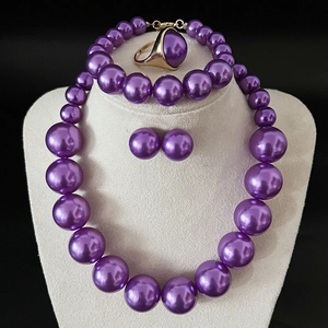 Detailed set of purple pearl necklace, bracelet and earrings on a jewelry display stand