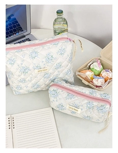 Foto lifestyle di trousse trapuntate con fiori blu e chiusura lampo rosa vivace