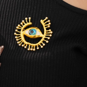 Detail view of a vintage evil eye brooch with blue resin and crystals on black fabric