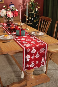Close-up of red Christmas table runner with white snowflake patterns and white tassels