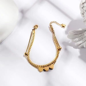 Detail of gold double-layered bracelet with heart pendants and snake chain on white base