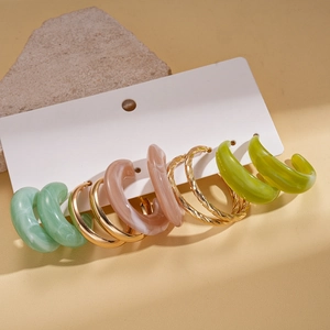 Detail of 5-pair acrylic resin C-shape hoop earring set on textured stone backdrop
