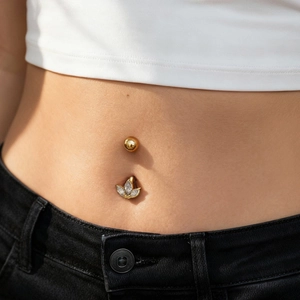 Zirconia navel piercing jewelry on model with gold and silver leaf design accents