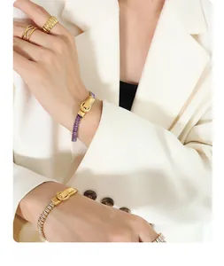 Detail of gold-plated bracelet with belt buckle clasp and multicolored zirconia stones