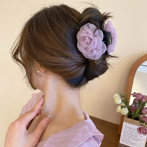 Detail einer violetten Organza-Blumen-Haarklammer, getragen von einem Modell im Innenbereich