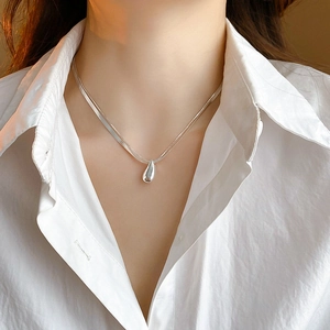 Detail of a minimalist double-layer silver water drop necklace on a female neck