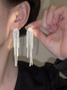 Close-up of shimmering silver tassel earrings worn by a model for elegant evening looks