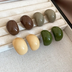 Detailed view of minimalist acrylic bean-shaped earrings in four earthy matte colors