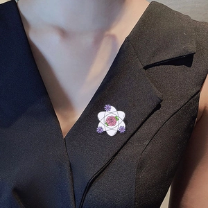 Enamel science pin with atomic structure and pink rose on a black blazer lapel