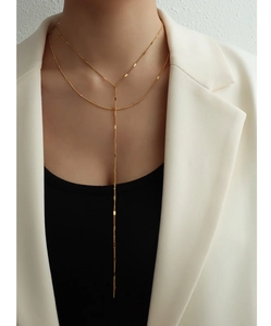 Detail of a double-layered 18k gold-plated Y-shaped necklace with long tassel pendant