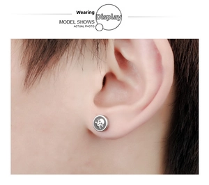 Gros plan d'une boucle d'oreille crâne en argent de style punk portée sur un homme