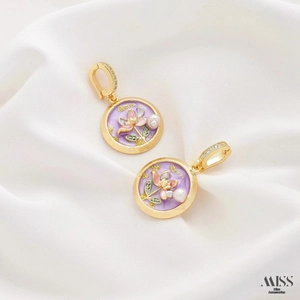 Detailed close-up of floral enamel earrings with pearls on white silk background