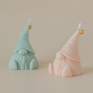 Handmade Santa Gnome scented candles in mint green and pink with festive gold bell charms