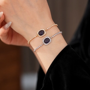 Detailed view of silver and gold bracelets with purple oval gemstones and white crystals