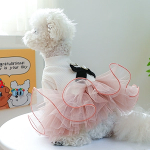 Detail of pink tiered mesh pet dress with black velvet bow and pearl on a white dog