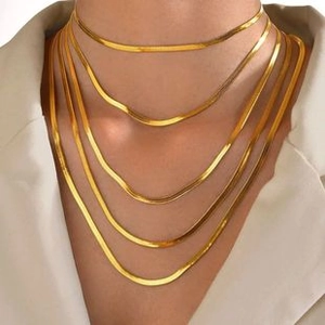 Layered gold snake chain necklace shown on model wearing a chic beige blazer