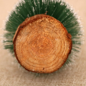 Detail of solid wood base with annual rings on a snowy LED Christmas tree