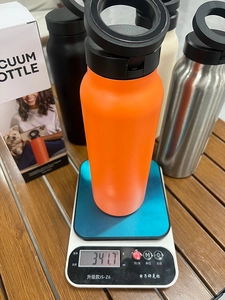 Precision scale weighing an orange vacuum insulated water bottle at 341.7 grams