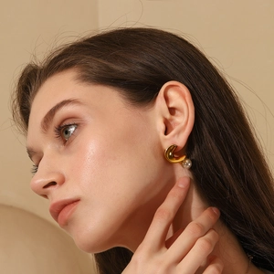 Close-up of 18K gold plated twisted earrings with elegant pearl detail on model