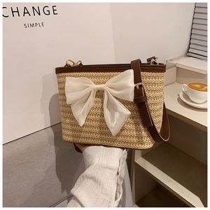 Detail of woven straw bucket bag with large cream mesh bow and brown leather trim