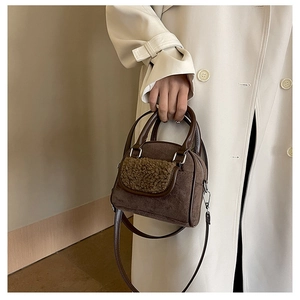 Detail shot of plush shearling trim and faux leather strap on small brown tote bag