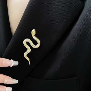 Detailed view of a gold-plated snake brooch with sparkling cubic zirconia on a black blazer