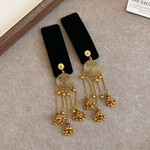 Macro view of retro golden ethnic jhumka earrings with long tassel chains and bells