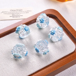Macro shot of five glass beads with hand-painted blue flowers for DIY jewelry crafts