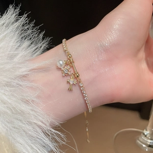 Detail of adjustable gold bracelet with zircon cross, star pendant and pearl on wrist