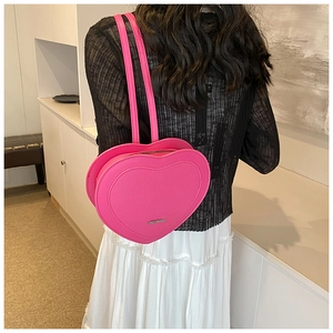 Pink heart-shaped backpack with embossed letters worn by model in a stylish setting