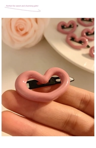Close-up of pink hollow heart hair clip on a black metal base for women's styling