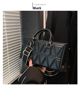 Detail of black triangular quilted handbag with gold hardware and wide shoulder strap