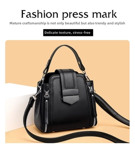Detail of black leather handbag featuring V-shaped stitching and metal shield buckle closure