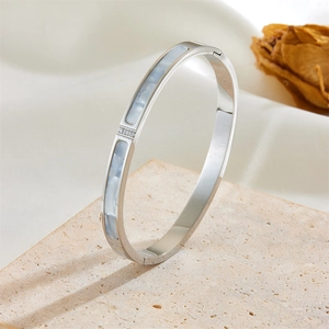 Silver titanium steel bangle with shell inlay and three zircons on sandstone background