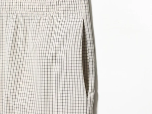 Detail of plaid nylon pants featuring elastic waistband, side pockets and woven texture