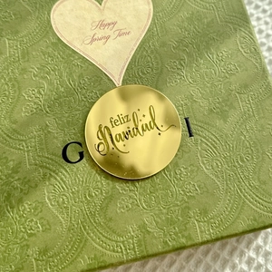 Detailed view of green paisley embossed gift box with Feliz Navidad gold label decoration