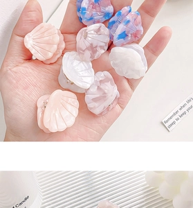 Macro detail of eight colorful shell-shaped mini hair claws in resin and acrylic