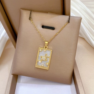 Close-up of golden Tarot pendant with The World engraving and celestial pearls