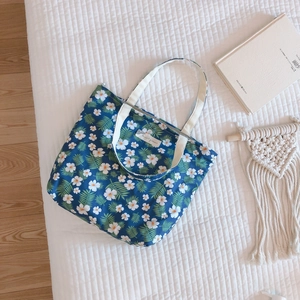 Detailed view of dark blue floral cotton tote bag with interior label on cream quilted background