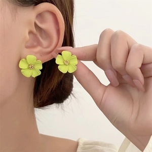 Nahaufnahme gelber Blumenohrstecker mit Diamanten am Ohr eines Models