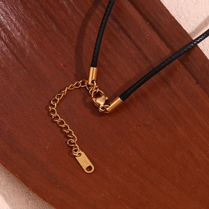 Macro shot of 18K gold plated clasp and black braided leather cord with extension chain