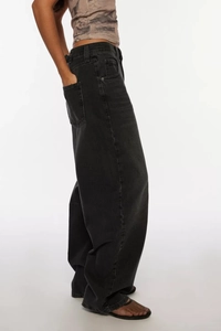 Side view of washed black wide-leg jeans showing baggy fit and denim texture on model