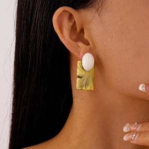 Gros plan d'un modèle portant des boucles d'oreilles vintage en résine marbrée jaune et noir