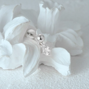 Close-up of silver cartilage stud with cz stone and ball on floral background