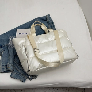 Macro detail of white quilted travel bag with reinforced straps and soft texture