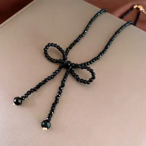 Elegant black faceted bead necklace featuring a bow-knot design and gold-tone accents