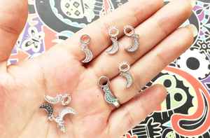 Detailed close-up of silver moon pendants with inlaid zircons held in a hand