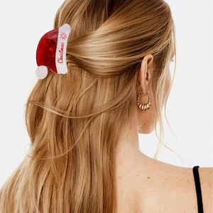 Detail of red and white Christmas hat hair claw clip with snowflake pattern and text